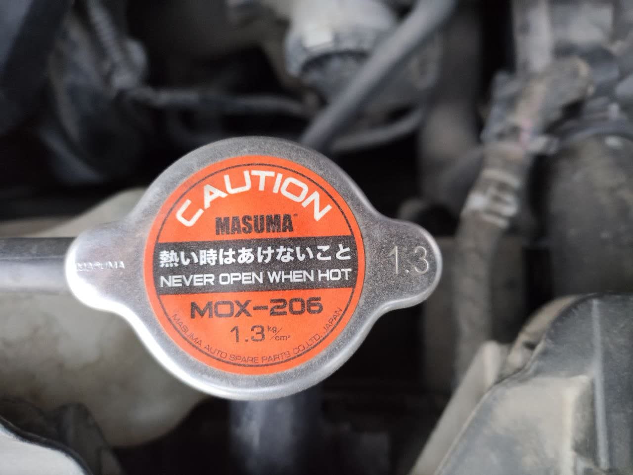Photo of MASUMA MOX-206 radiator cap showing the 1.3 bar (1.3 kg/cm²) pressure specification label