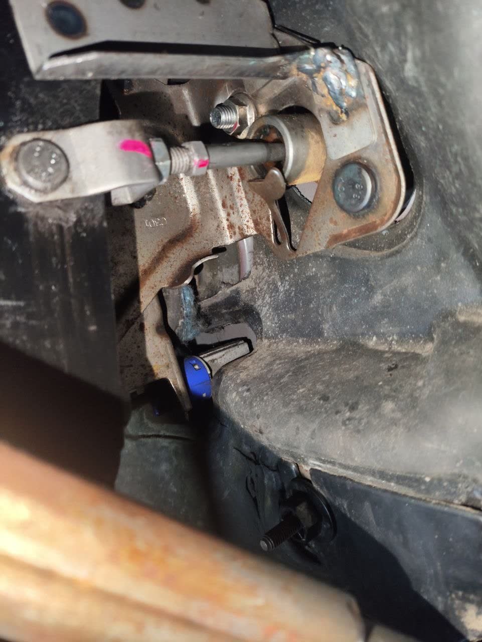 Fractured clutch pedal side mounting bracket, photographed from inside the cabin; the break follows the weld line and shows visibly poor-quality metal at the fracture face