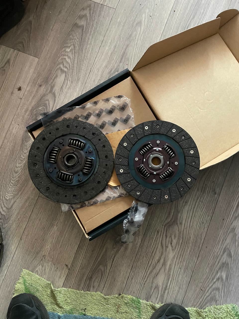 Two clutch discs on a box, one new and one worn, the newer one identified by the poster