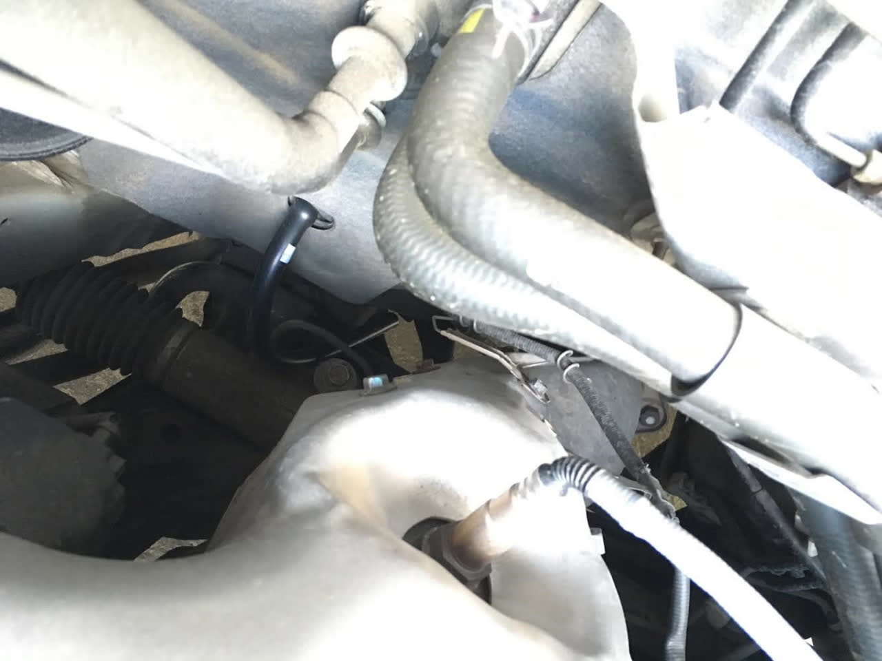 Photo of the extended black drain hose solution, properly routed outside the vehicle body