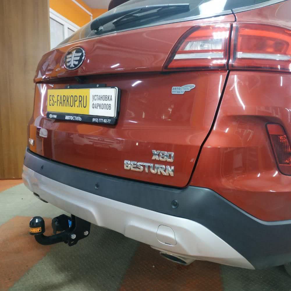 Rear of an orange/copper X80 Besturn showing a black ball-mount tow hitch installed under the rear bumper, with an "ES-FARKOP.RU — Установка фаркопов" installer branding plate on the license plate frame