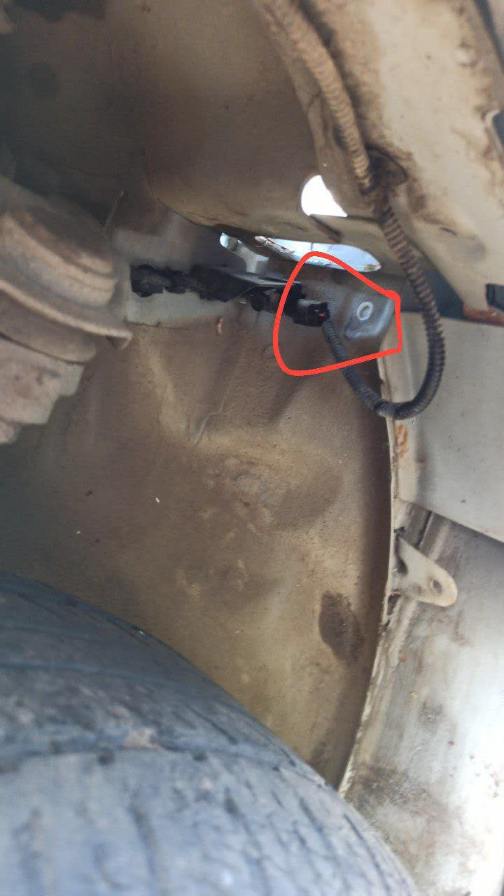 Close-up photo of the uncovered drain hole under the fender before sealing