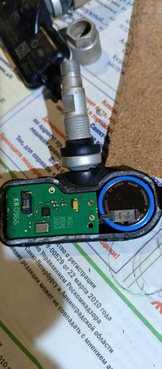 Disassembled TPMS sensor showing the CR2050-type battery compartment inside a cut-open casing