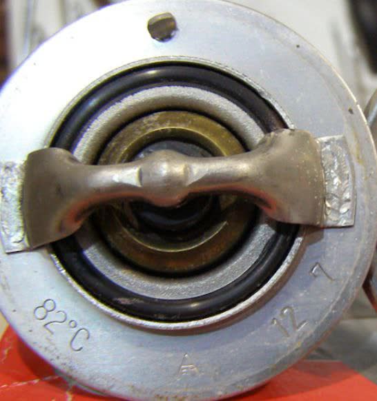Back side of a removed thermostat showing the stamped opening-temperature marking, used to verify true spec vs. listing claim