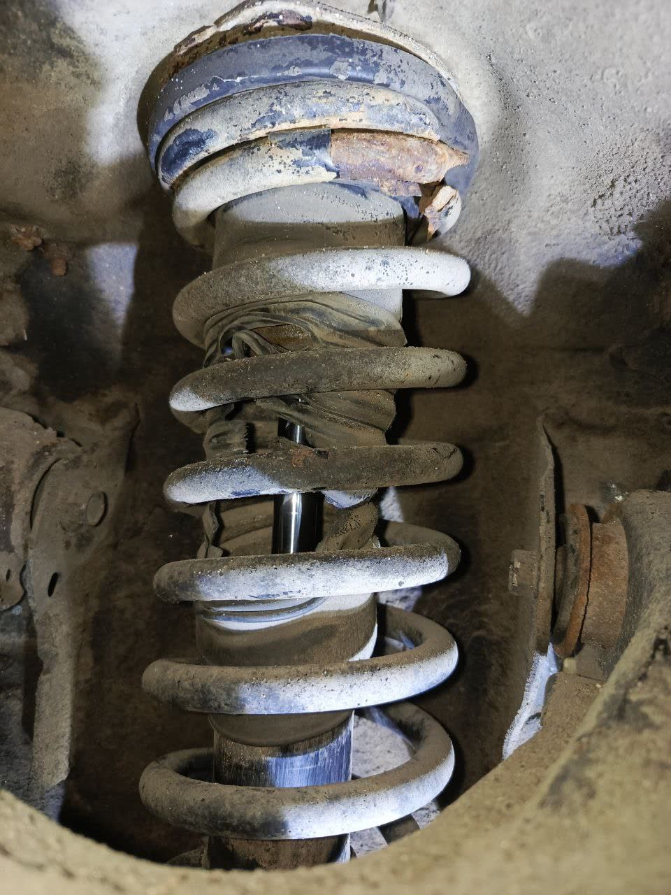 Broken front suspension spring showing fatigue failure