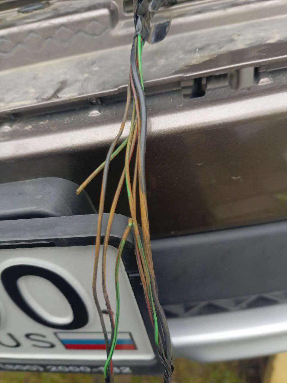 Close-up of the exposed wiring harness showing oxidation and physical damage