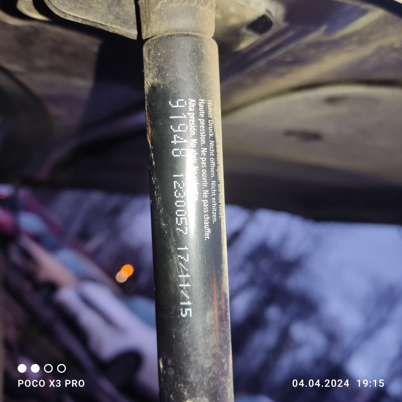 Dusty/used trunk strut with visible Chinese manufacturing markings — generic aftermarket unit in poor condition