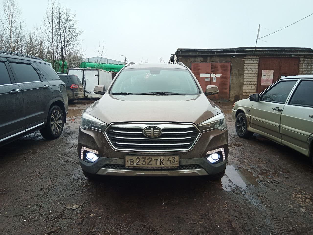 Completed fog light installation on a white X80 (Kaliningrad plate visible), fog lights illuminated