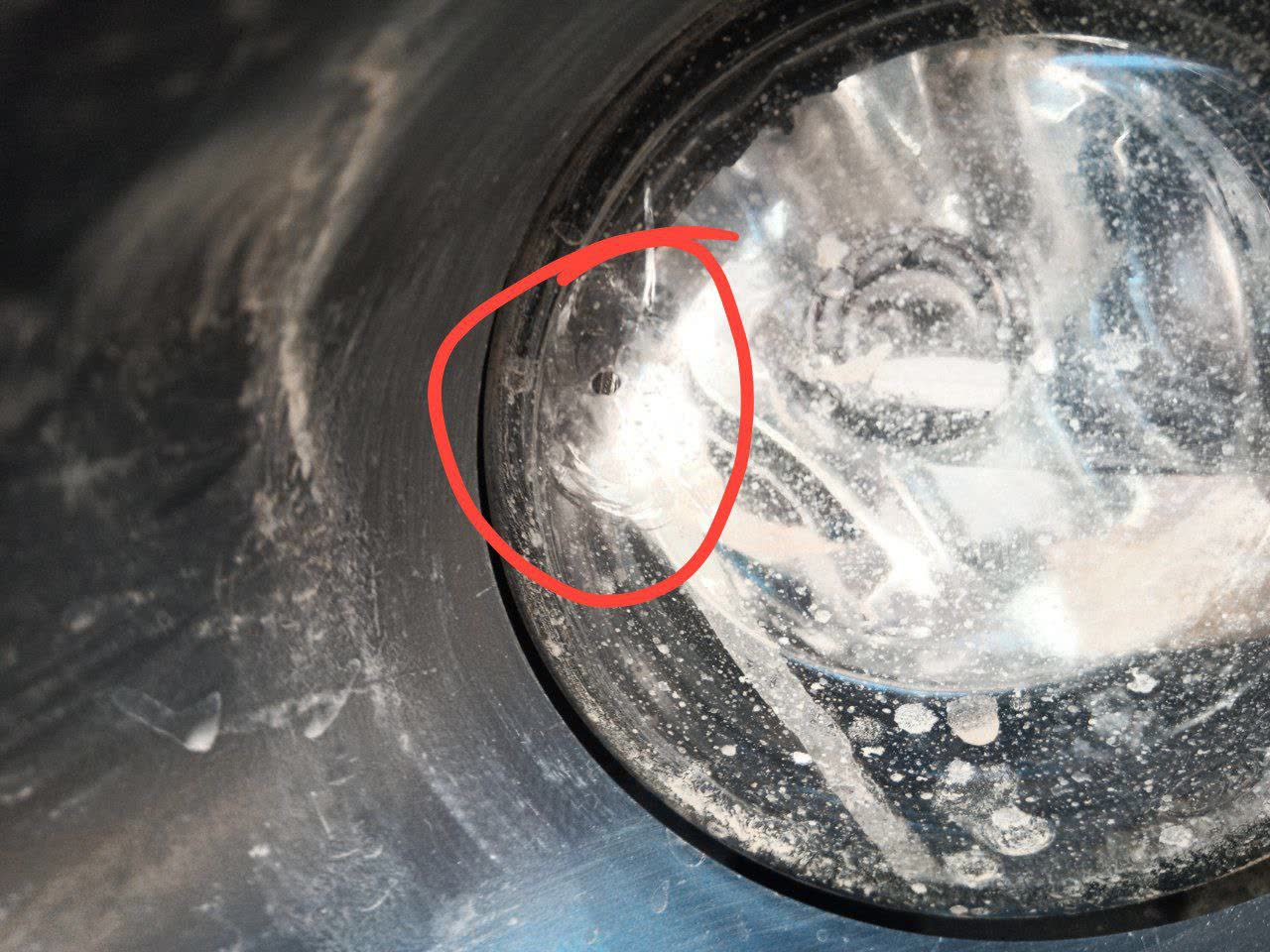 Photo of a fog light with a visible chip/crack from a road-stone impact