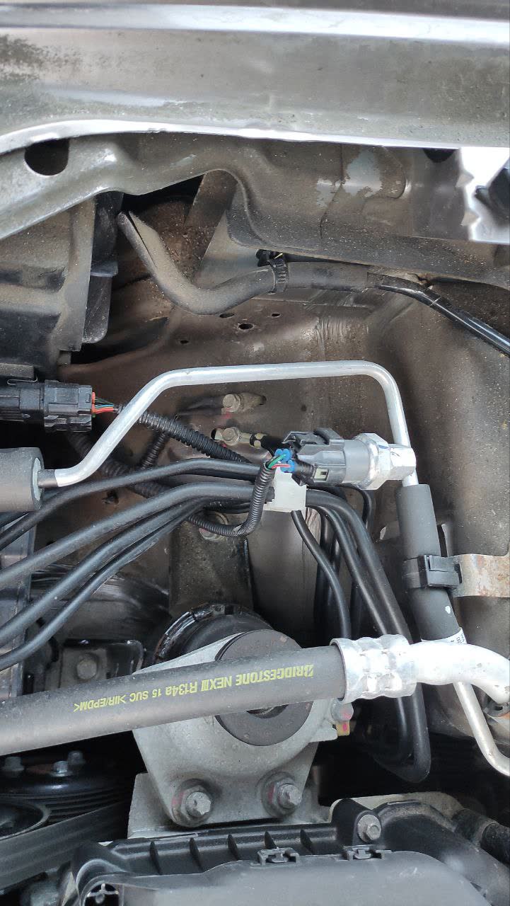 Photo of the engine bay showing the cut hose behind the right headlight (suspected adsorber line)