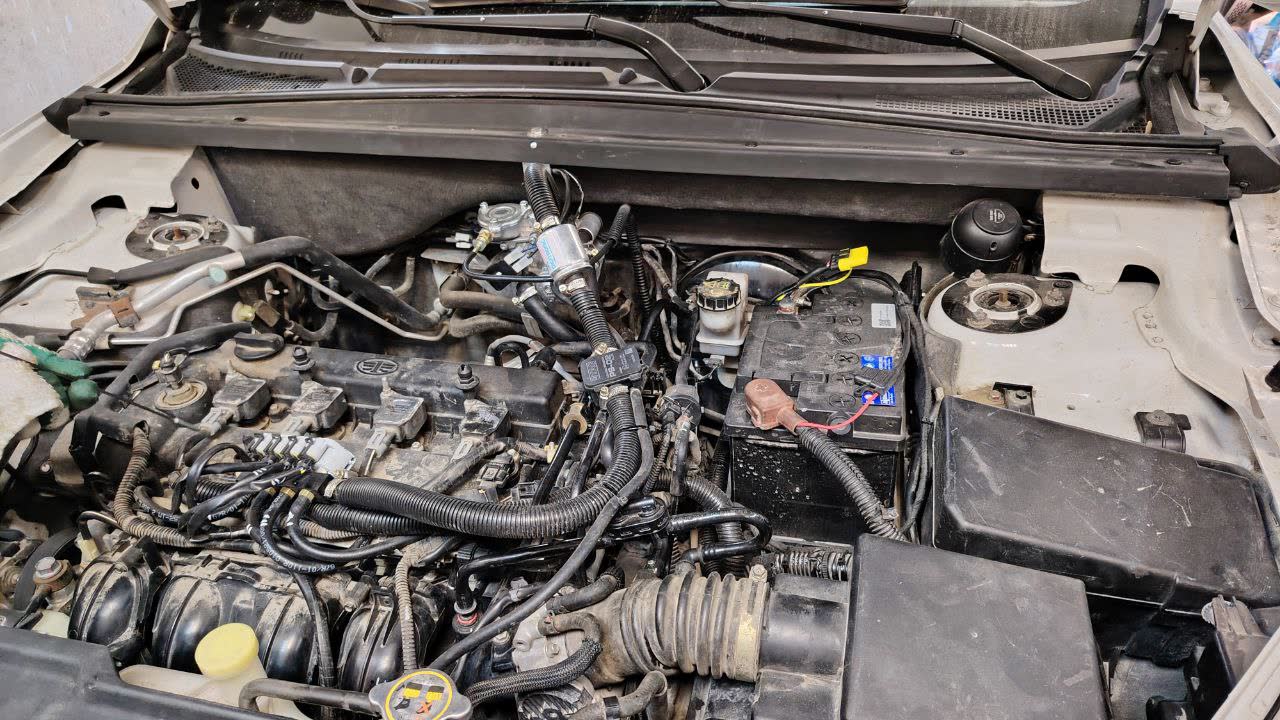 Engine bay photo showing a GBO installation with the reducer mounted above the optimal height — demonstrates a common improper installation pattern