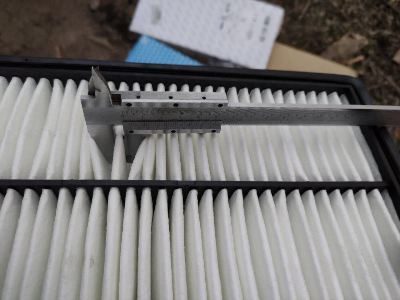 Calipers measuring filter element thickness, demonstrating the measurement methodology used for the comparison
