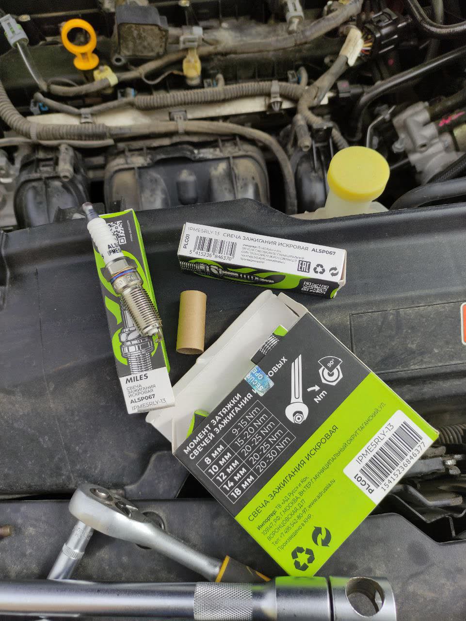 Miles ALSP067 iridium spark plugs shown with packaging and installed components in the engine bay