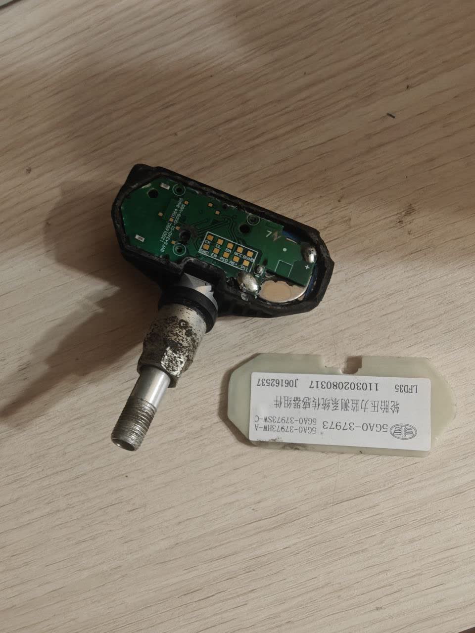 TPMS sensor disassembled, showing battery location inside epoxy-sealed housing