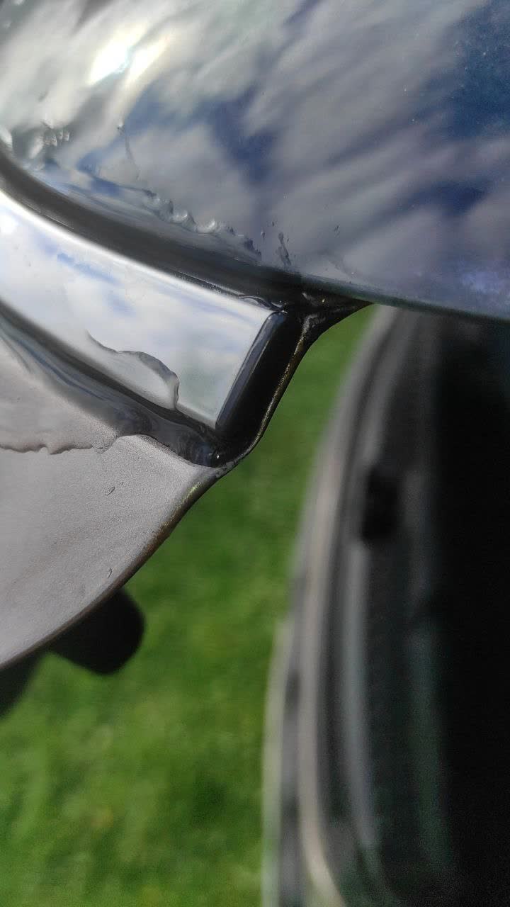 Photo showing rust and paint oxidation under chrome trim at the tailgate corner