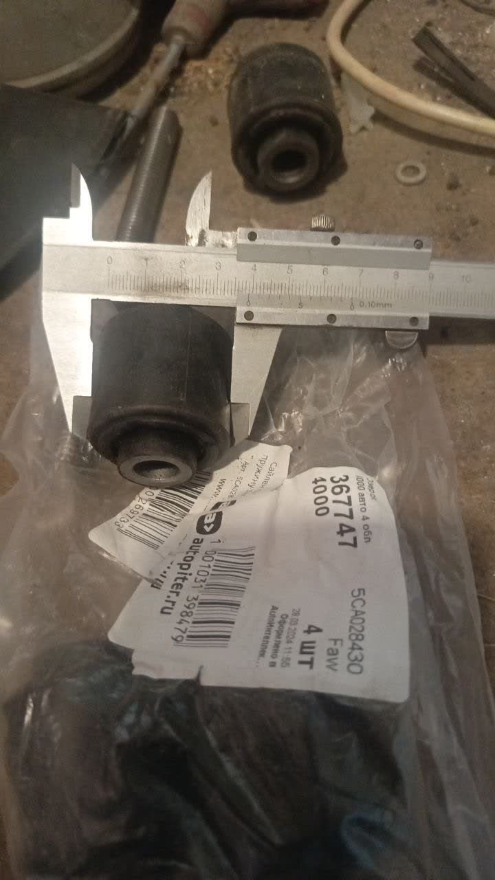 Comparison photo showing the aftermarket rear cross-member bushing's rubber outer shell next to the OEM part's metal outer shell, illustrating the incompatibility