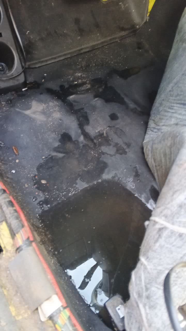 Photo showing water accumulation on the driver's side floor, linked to a loosened sunroof-drain fitting above the BSM block