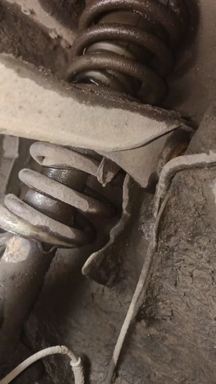 Close-up of the spring visibly bent/damaged beneath the torn boot