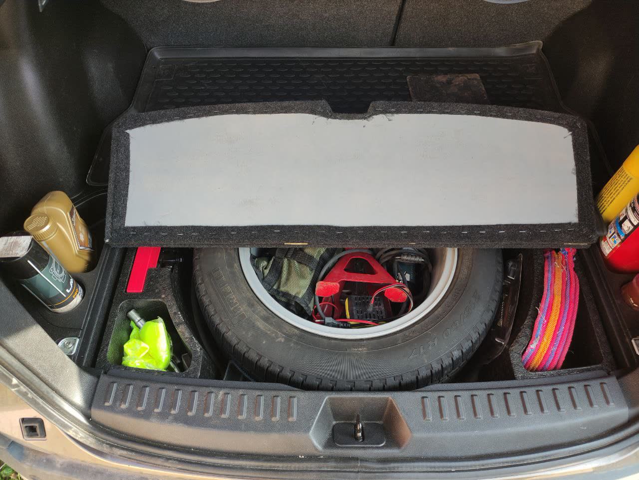 Contents of the emergency kit laid out: tool set, compressor, cables, shovel, and spare fluids