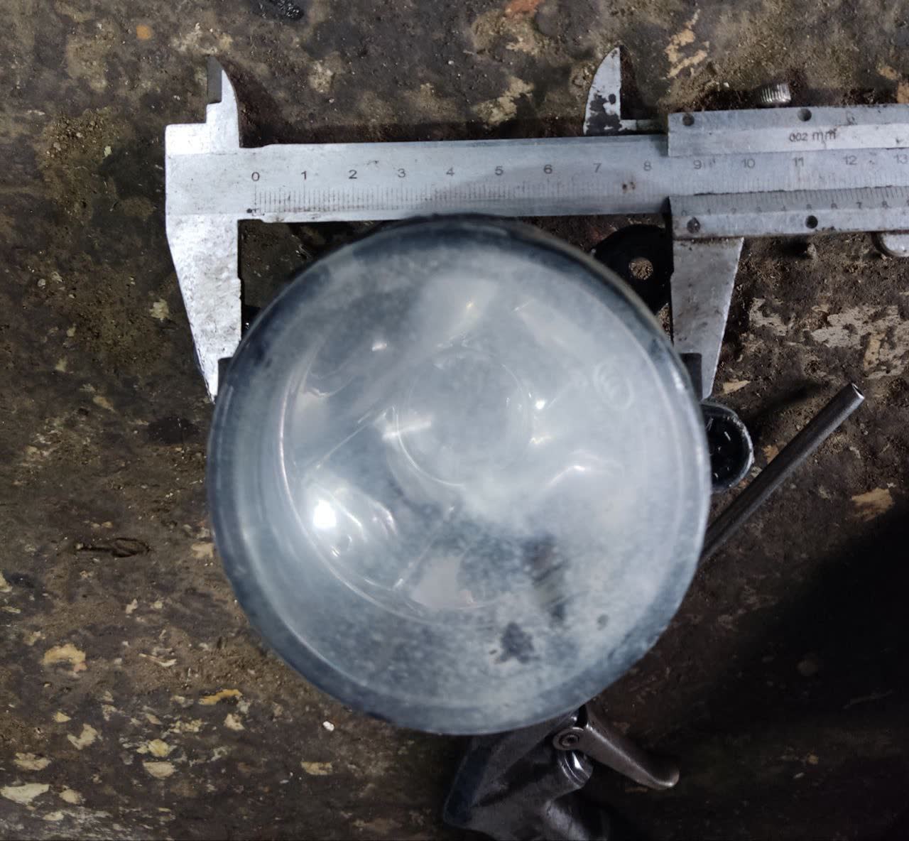 Photo of pre-facelift fog light lens measured with a caliper showing ~70mm diameter