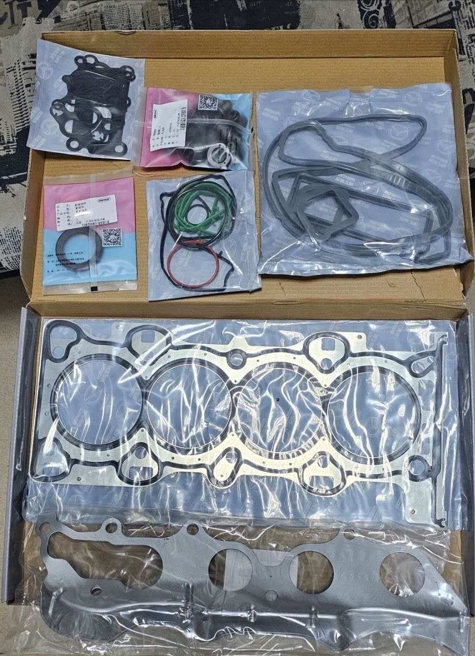 Photo shows a valve cover gasket kit with various seals and O-rings in a box, consistent with replacement gasket sets for the 4-cylinder engine