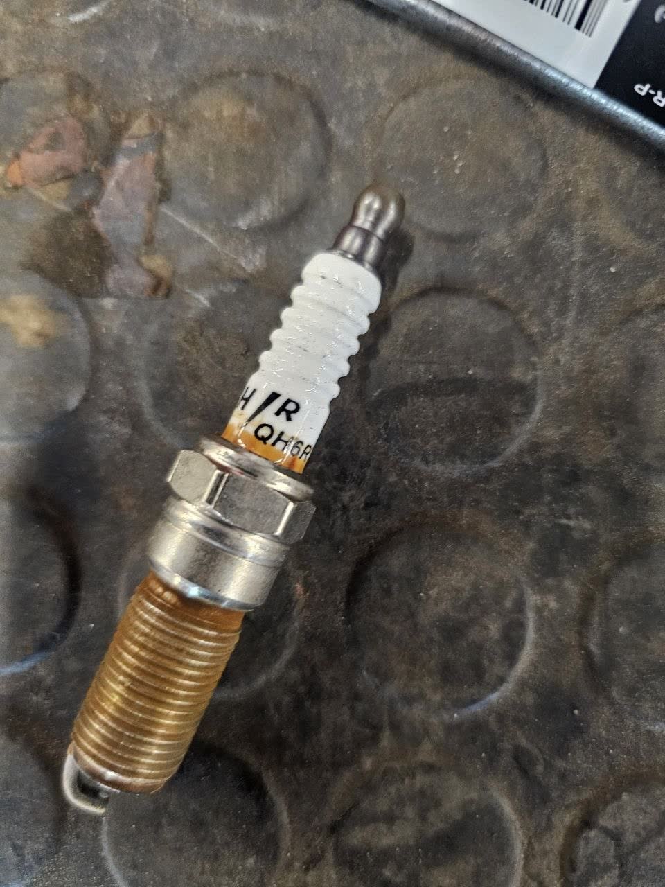 Spark plug removed after 30,000 km showing deposit accumulation