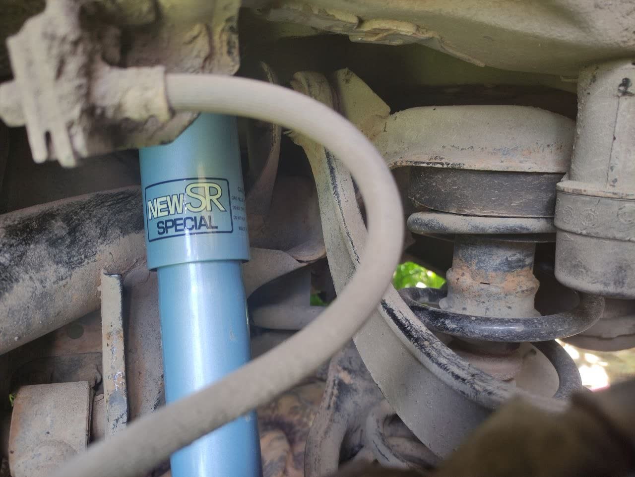 Rear shock removal sequence photo from under-car perspective, demonstrating access points