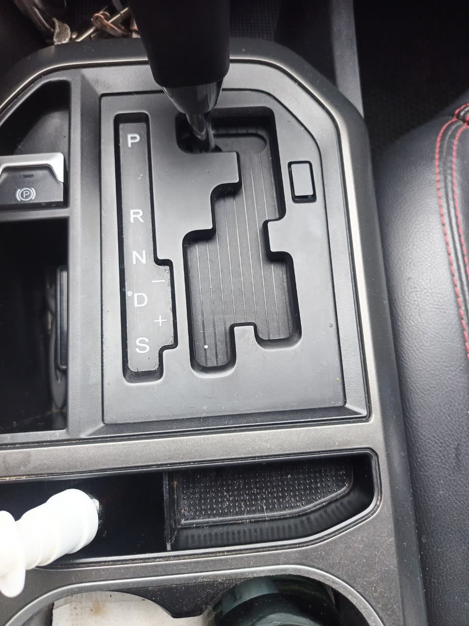 Photo showing the location of the mechanical selector-lock override button under the console cover