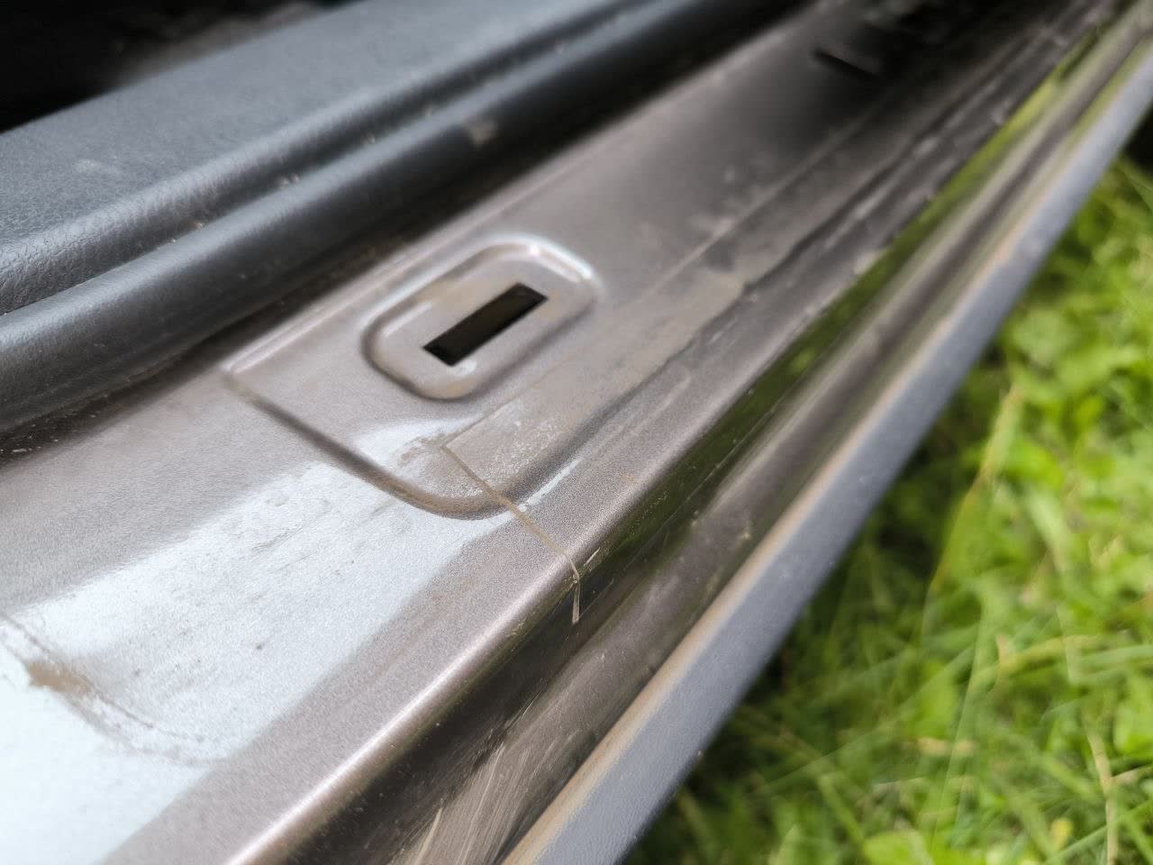 Photo showing protective film present on passenger-side door sill (clean) vs. missing on driver-side (visible rust/orange discoloration)