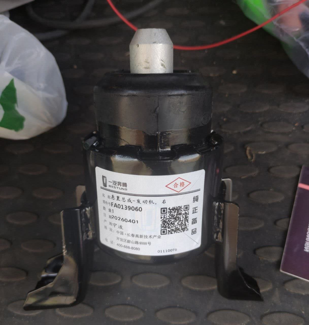 Photo of an engine mount showing a label with a QR code, Chinese/Russian FAW markings, and part-number engraving, disputed in the thread as possibly not genuine