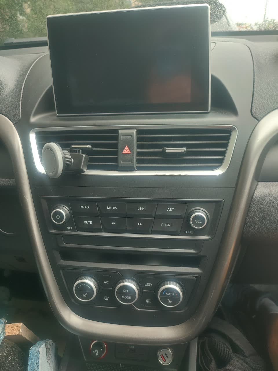 The head unit/dashboard photographed off — a blank black touchscreen and dark AC control cluster, showing the display, radio, and climate controls all dead at once