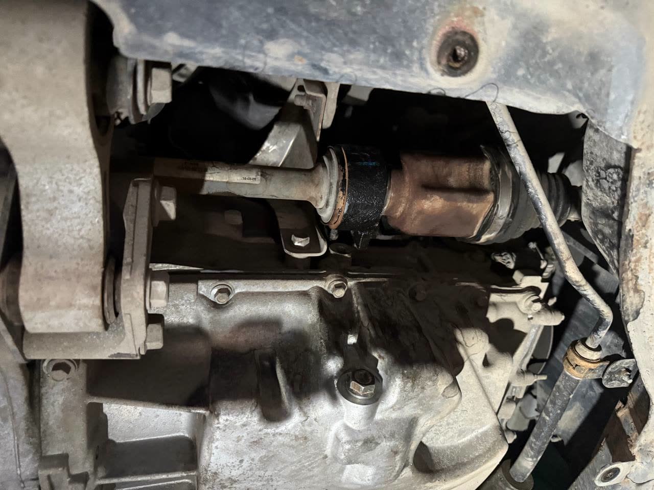 Photo of the gearbox side and shaft area with oily residue; no label marks the exact leak point