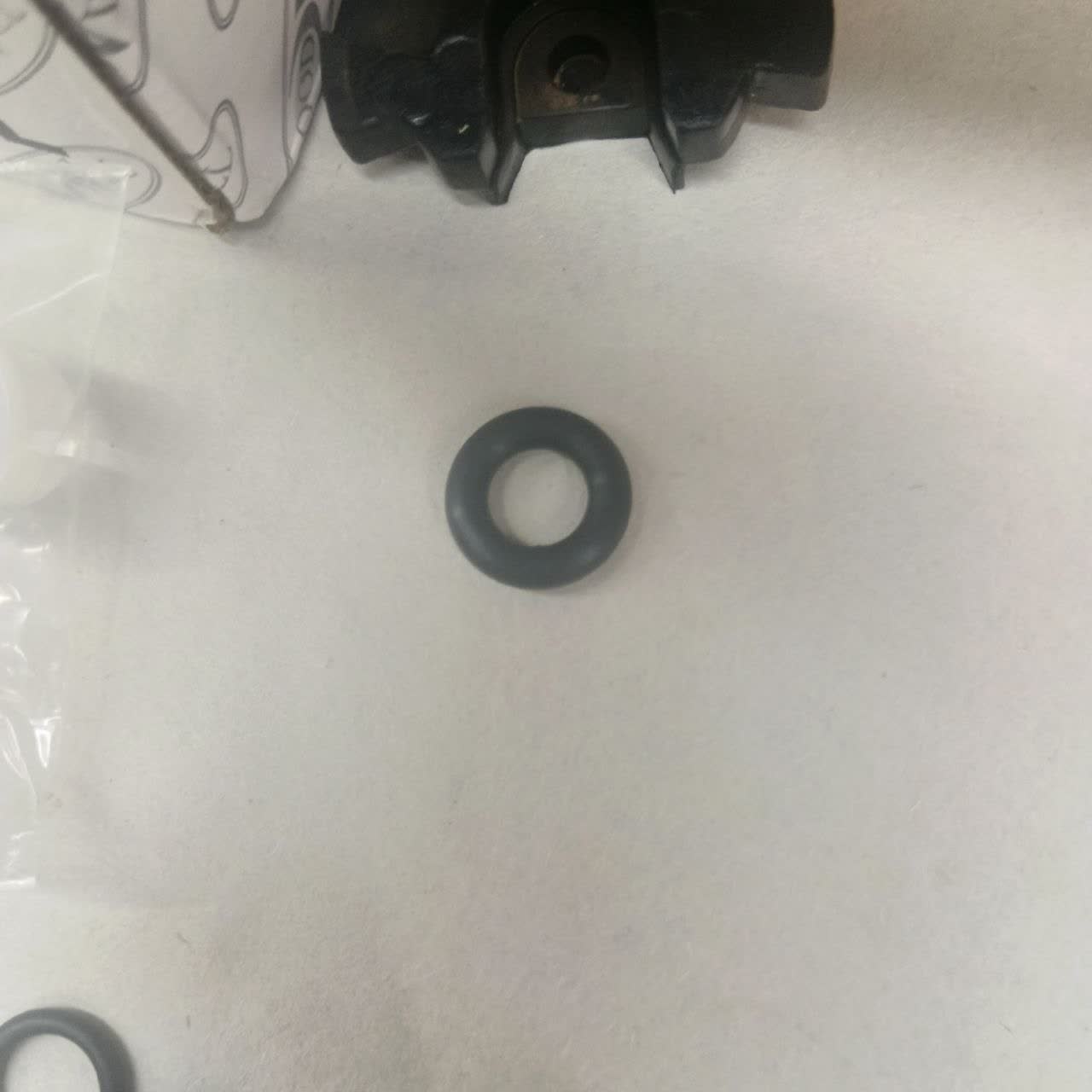 Small dark rubber O-ring from a fuel-fitting seal kit on a white surface