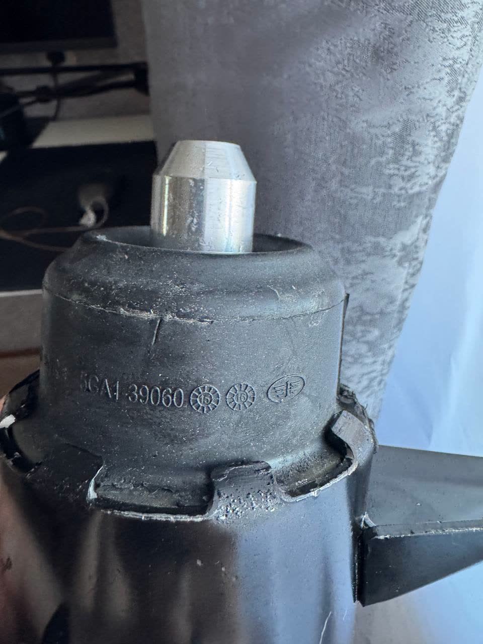 Removed black rubber engine mount with a metal stud on top; stamped "...GA1-39060" (leading characters cut off), a FAW logo and two round stamps