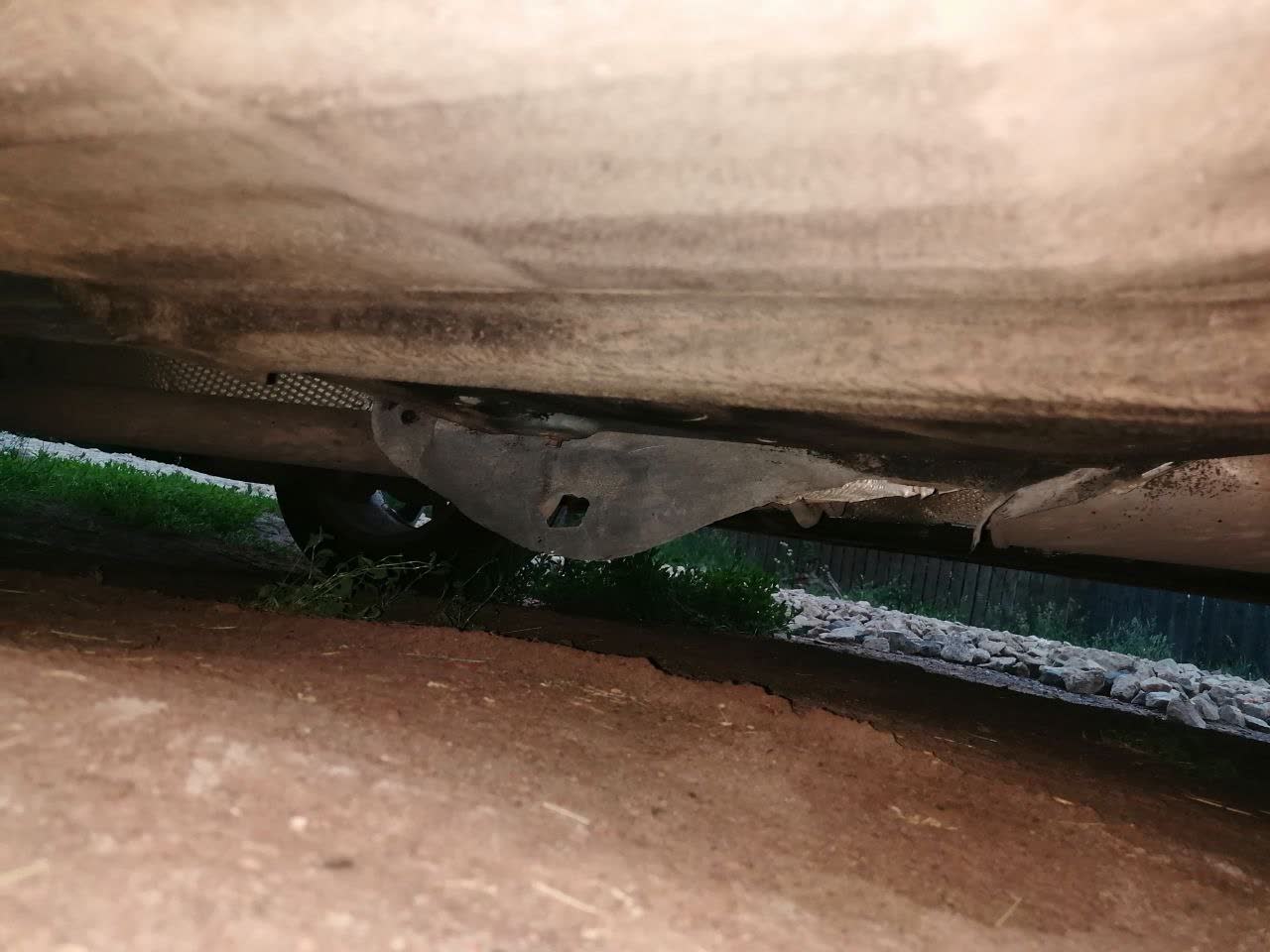 Photo of the muffler heat shield under the vehicle, showing the metal thermal-screen structure