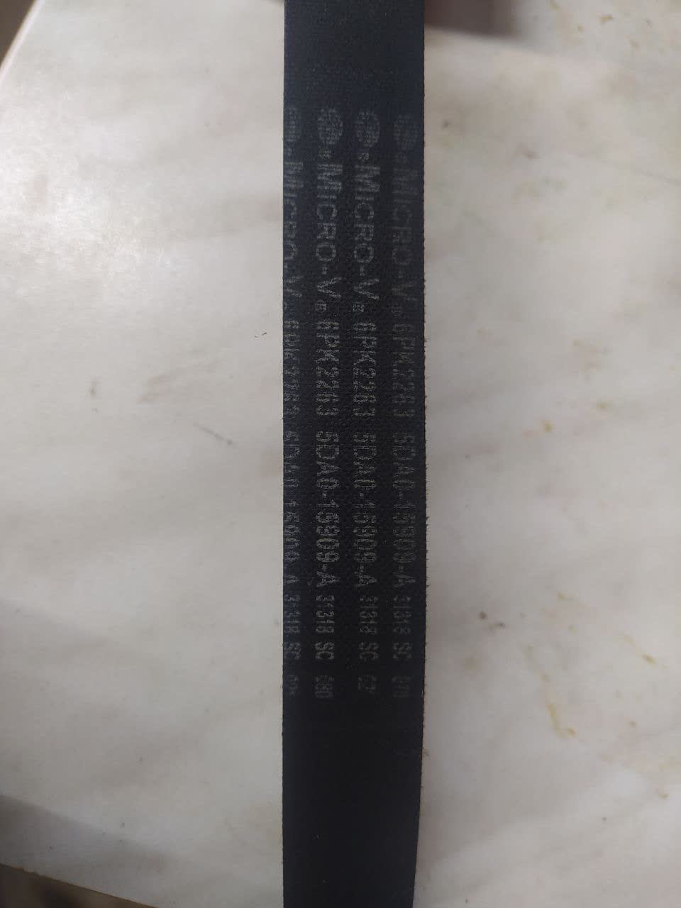 Close-up photo of the serpentine belt showing part number markings (6PK2263) etched into the rubber surface